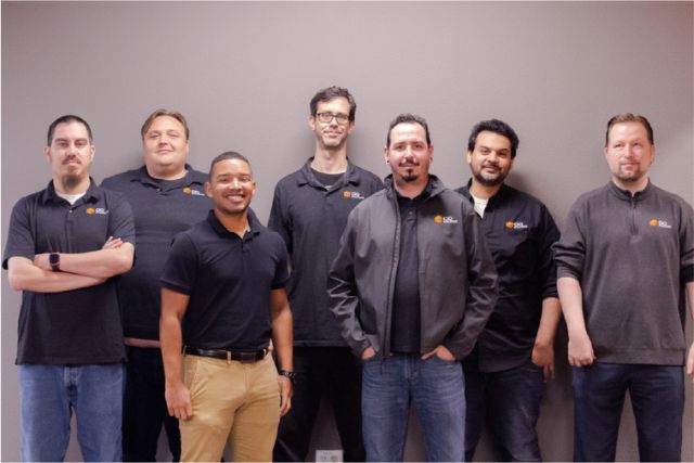 Group photo of CIO Solutions Fresno technical team standing in front of a gray wall